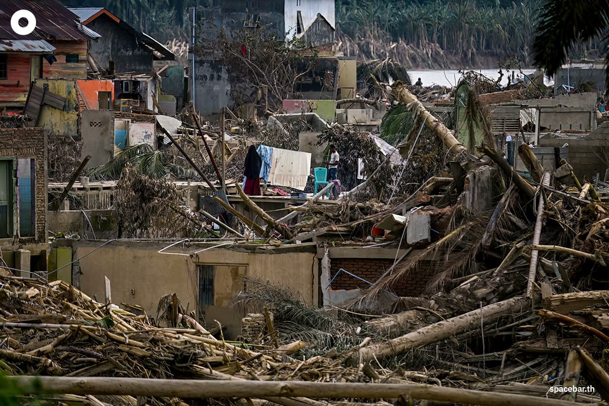 หญิงคนหนึ่งกำลังตากผ้าที่เพิ่งซักเสร็จท่ามกลางสภาพน้ำท่วมฉับพลันที่ถล่มลงมาในพื้นที่จังหวัดอาเจะห์ จังหวัดอาเจะห์ เมื่อวันที่ 6 ธันวาคม 2025 Photo by YT HARIONO / AFP