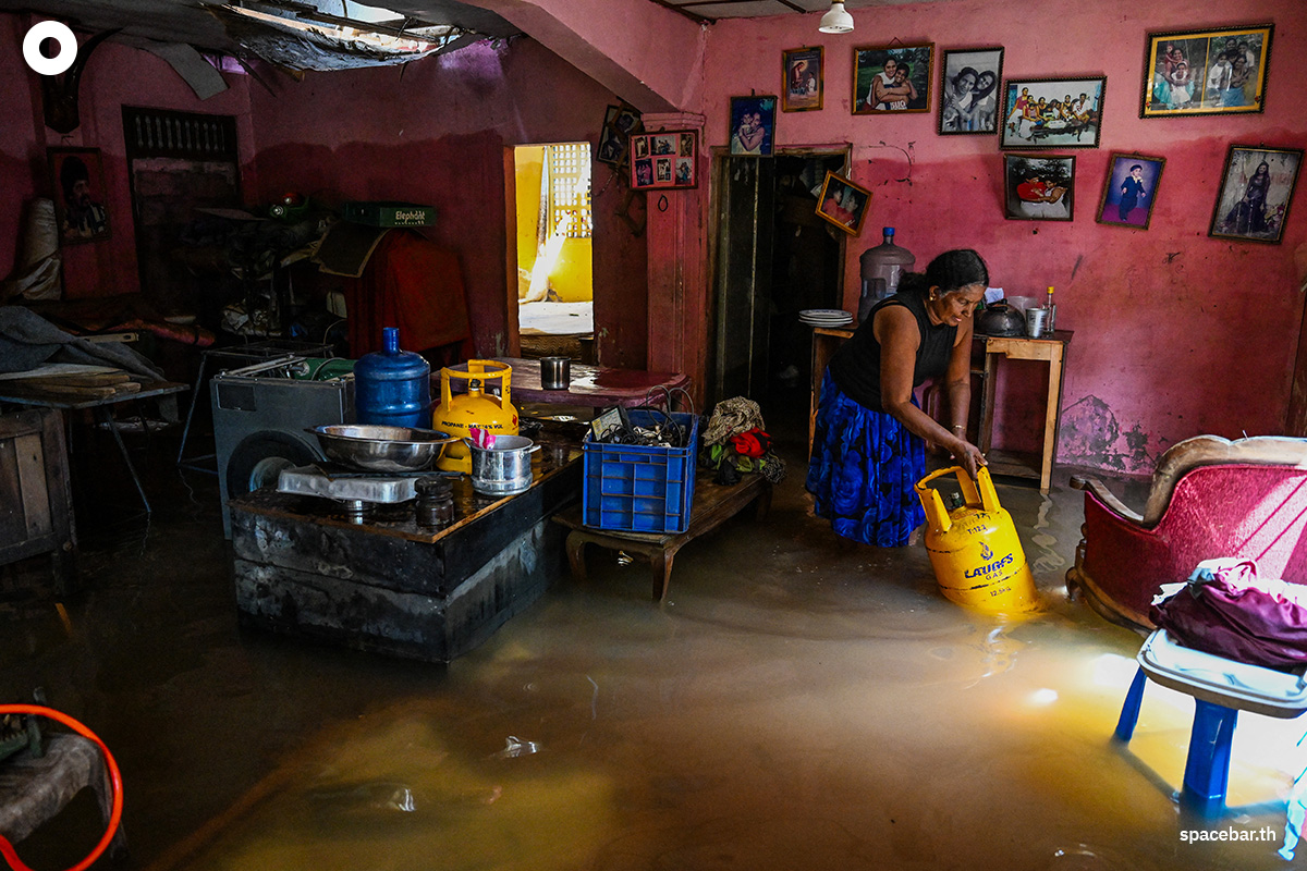 PhotoStory-   หญิงคนหนึ่งกำลังกลิ้งถังแก๊ส LPG ในบ้านที่ถูกน้ำท่วม หลังจากเกิดน้ำท่วมฉับพลันในเมืองเวลลัมปิติยา ชานเมืองโคลัมโบ ศรีลังกา เมื่อวันที่ 3 ธันวาคม 2025 (Photo by ISHARA S. KODIKARA / AFP) 