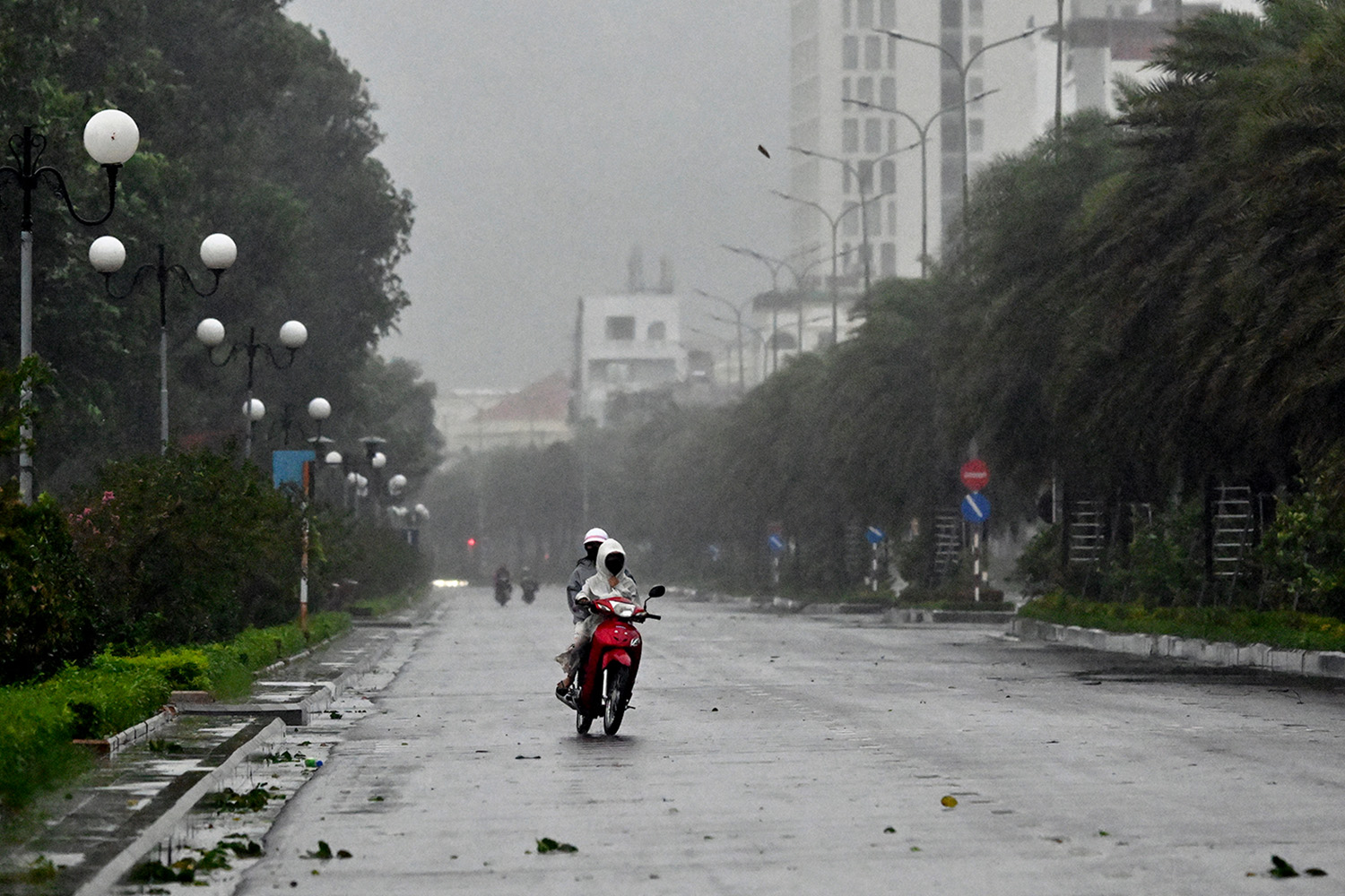 PhotoStory- ผู้ขับขี่รถจักรยานยนต์ท่ามกลางลมแรงก่อนที่พายุไต้ฝุ่นคัลแมกีจะพัดเข้ามา บนถนนใกล้ชายหาดกวีเญิน ในจังหวัดซาลาย ทางตอนกลางของเวียดนาม เมื่อวันที่ 6 พฤศจิกายน 2025 (Photo by NHAC NGUYEN / AFP)